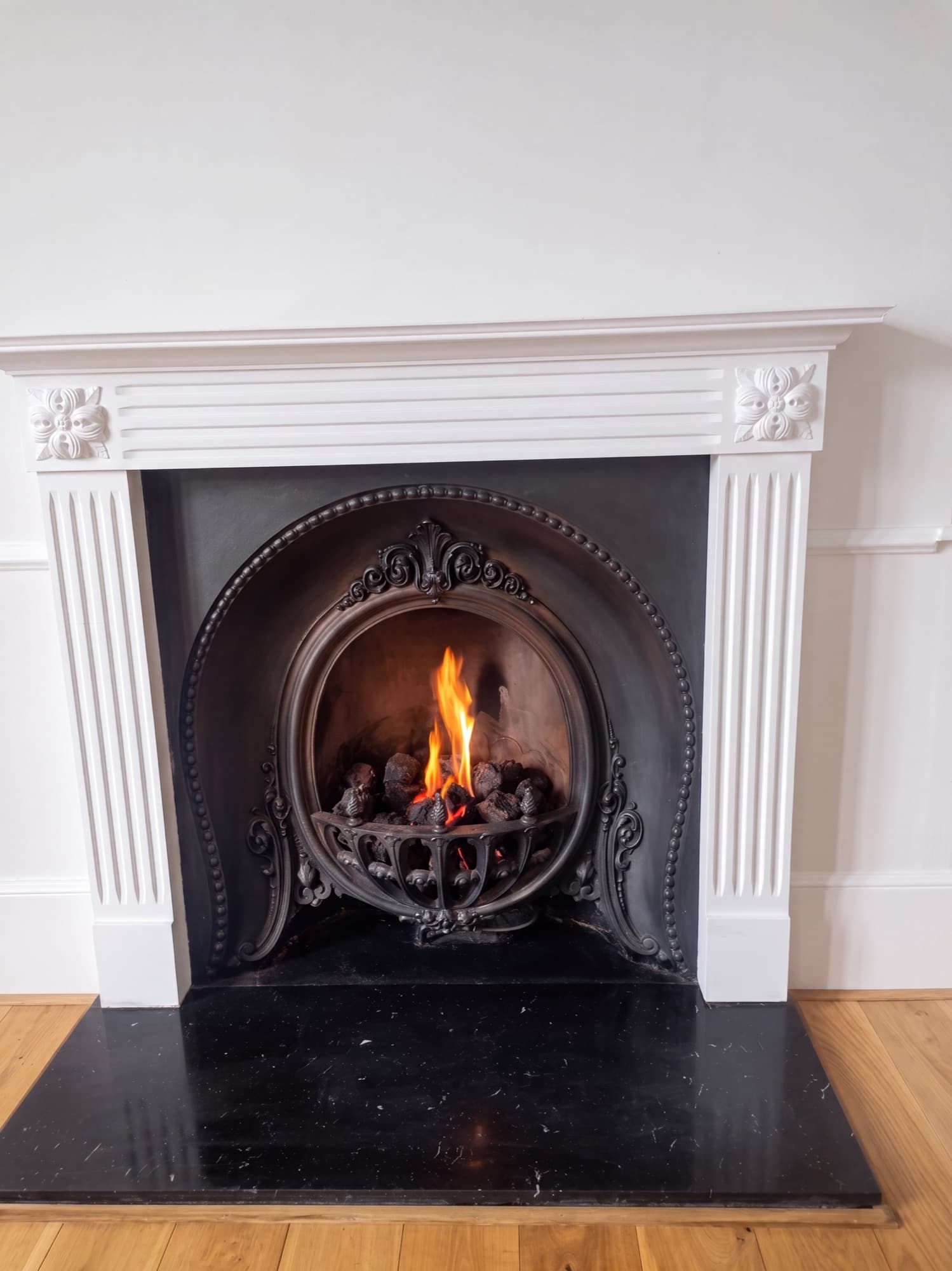 Lit gas fire in a period fireplace surround