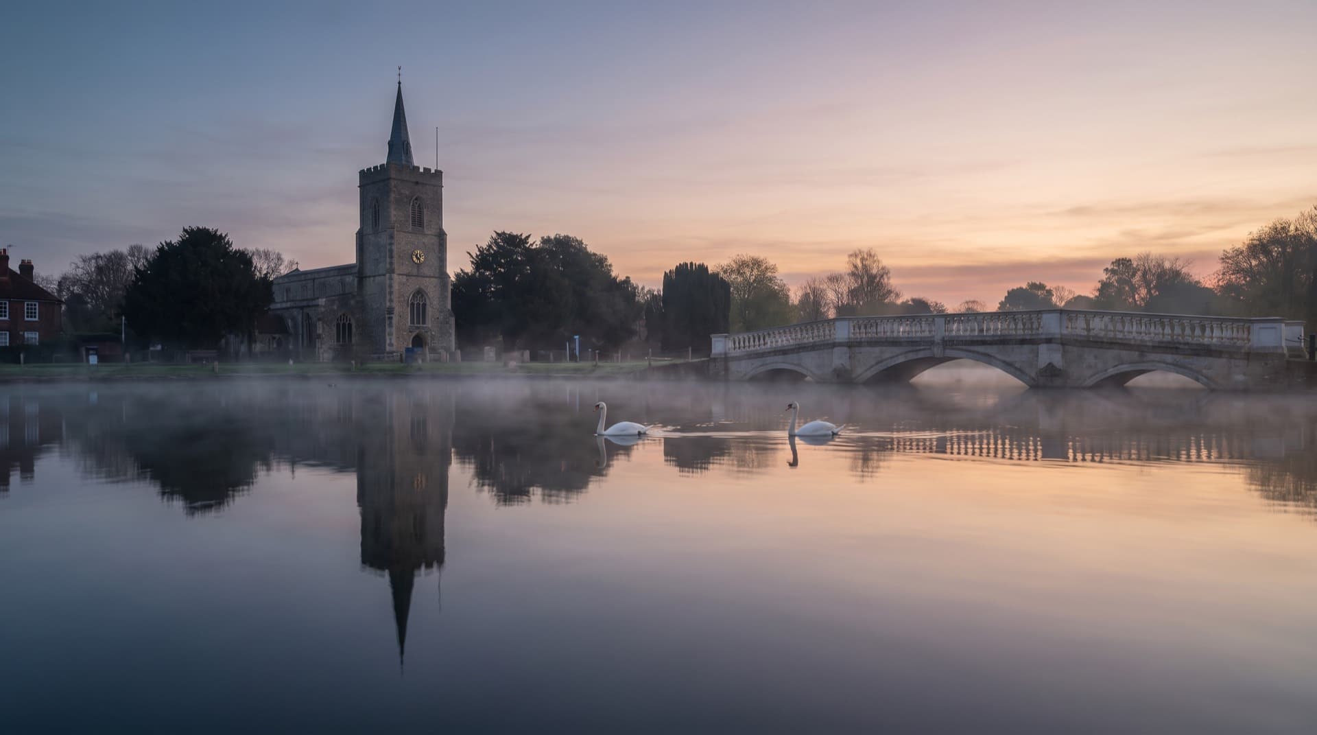Carshalton Ponds at dawn with the church tower reflected in still water