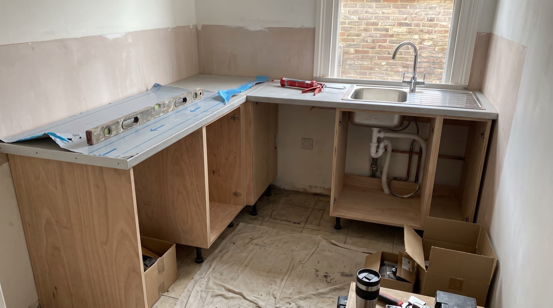 A kitchen mid-fit, with base units, worktops and the sink in place before the appliances are connected